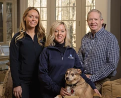 This is a photo of a mother, father, daughter, and dog posing for a photo. 