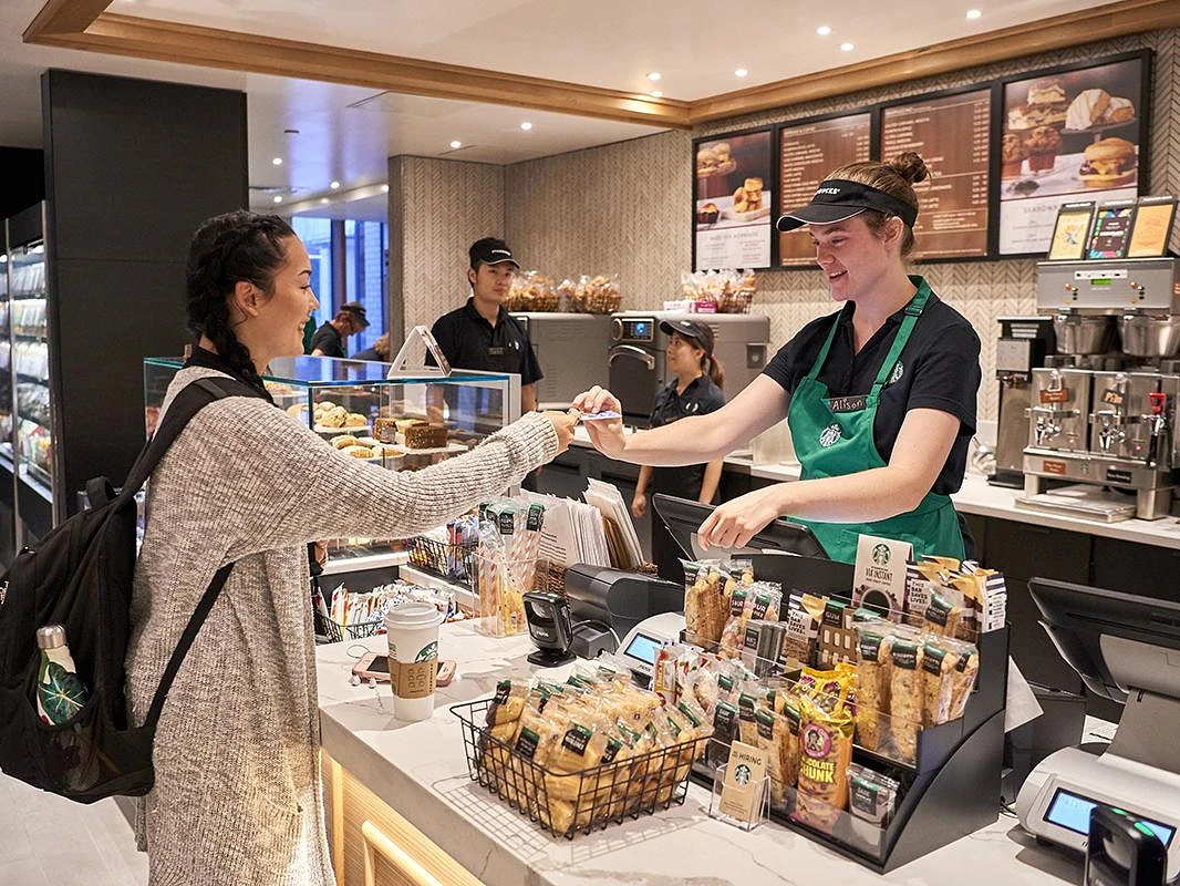 Student handing meal card to Starbucks employee at a coffee shop