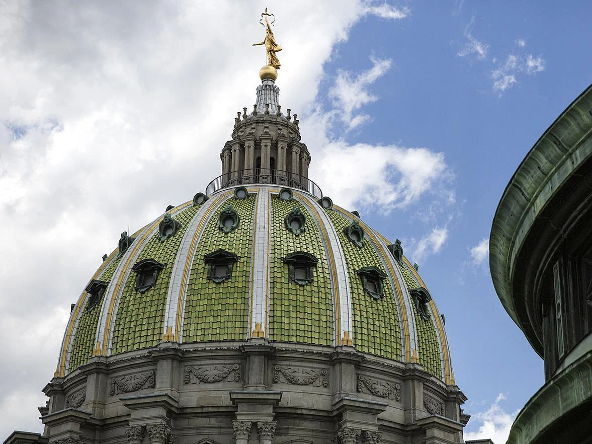 Dome of the Pennsylvania Capital Building against a clouded blue sky.