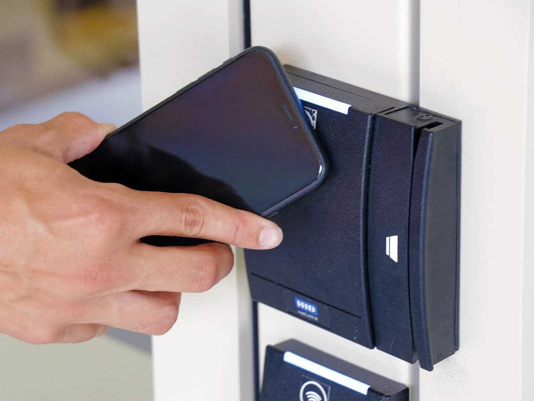 Phone unlocking a door next to a card reader.