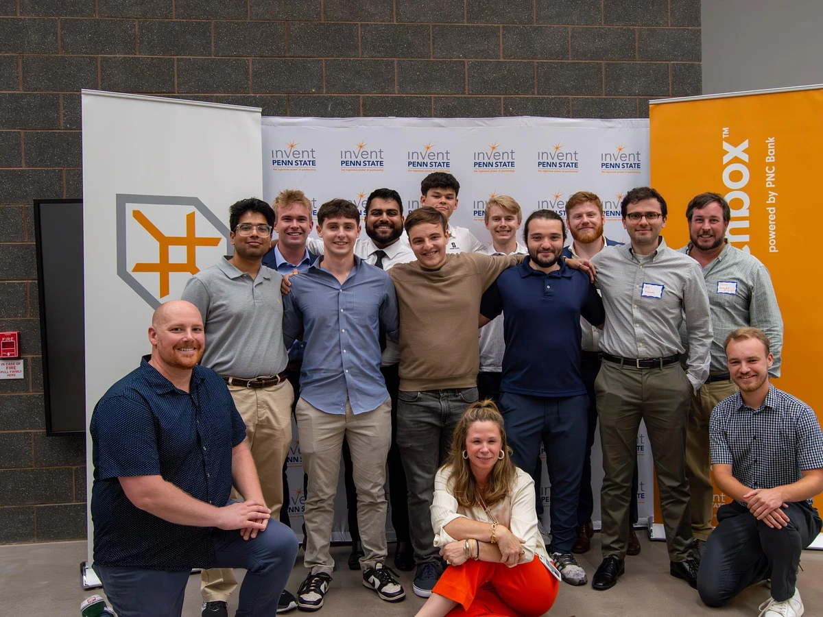 A group of people posing together in front of banners from Invent Penn State and PNC Bank.