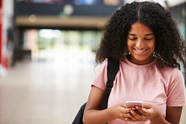 Student smiling at the cell phone they are holdin
